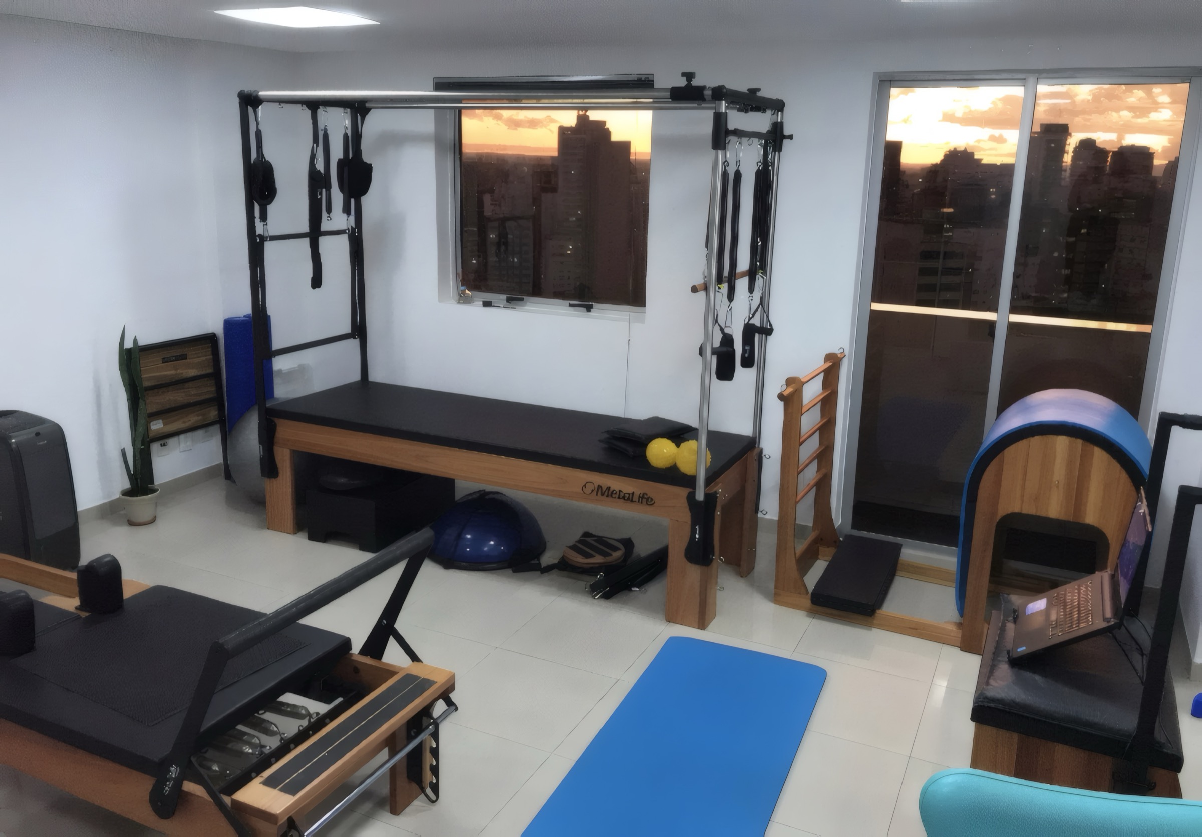 Sala do estúdio com Cadillac, Reformer e barril, e o pôr do sol de São Paulo pelas janelas